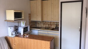 Une cuisine compacte dotée de meubles en bois, d’un four à micro-ondes, d’une machine à café et d’un évier.
