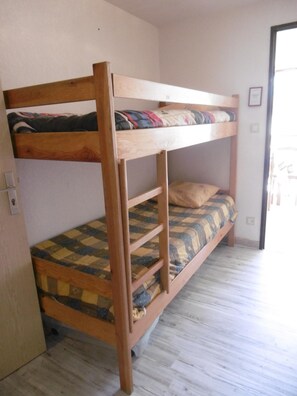 Ein Stockbett mit karierter Matratze und Holzrahmen.
