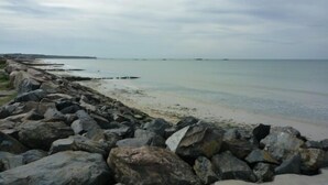 A rocky shoreline with calm water and overcast skies.