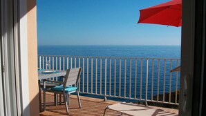 Een balkon met tafel en stoel, uitkijkend op een wateroppervlak.