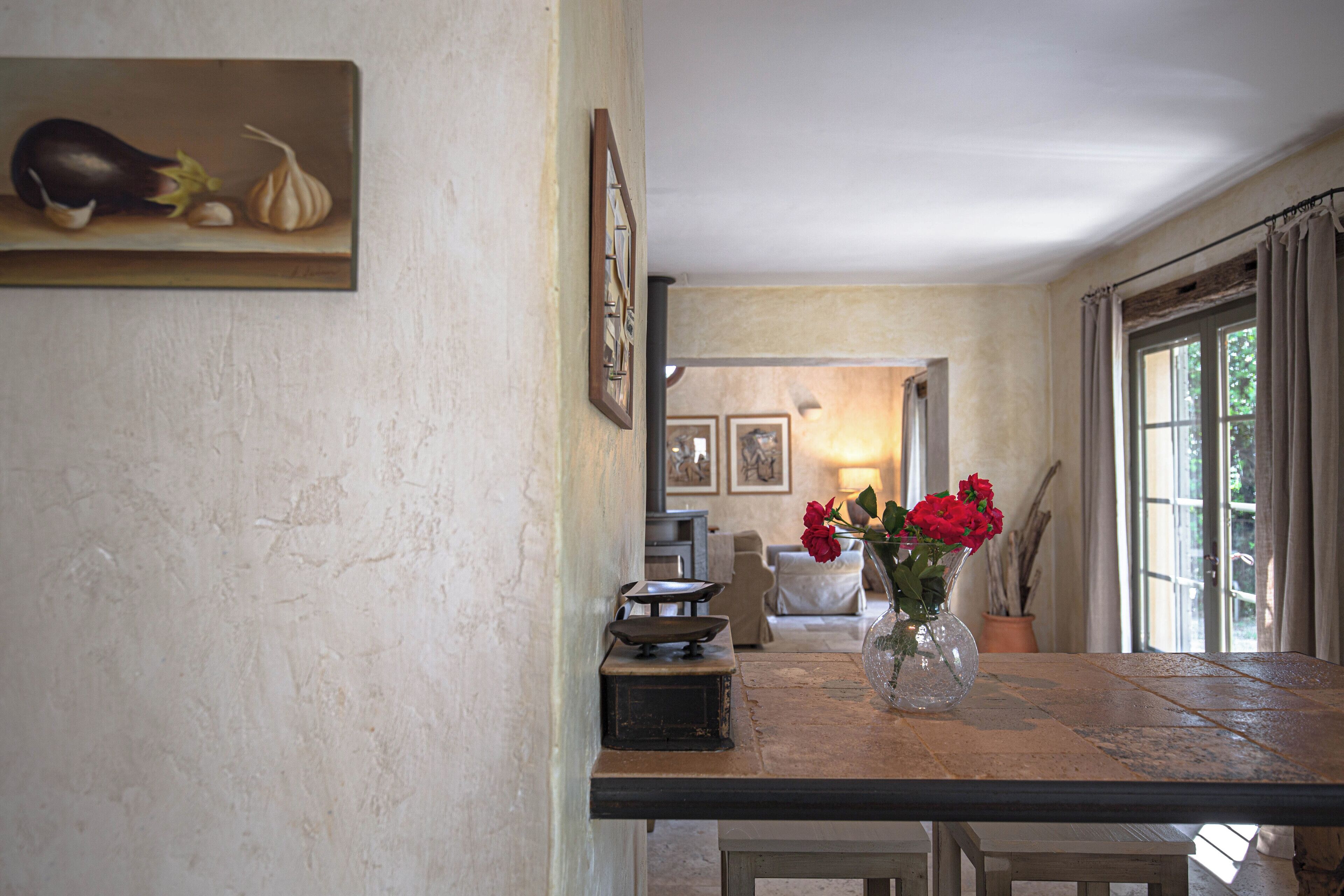 Un coin repas comprenant une table, des chaises, un vase avec des fleurs et un tableau accroché au mur.
