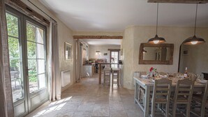 A spacious kitchen with a dining area, large windows, and a rustic ceiling. - Le mas des oliviers de Rustrel with swimming pool (Rustrel)