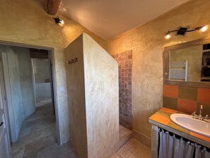 Une salle de bain avec une douche, un lavabo et un miroir.