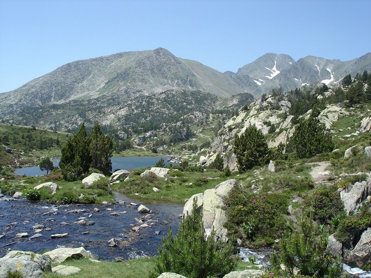 A mountainous landscape with a river, rocky terrain, and sparse vegetation.
