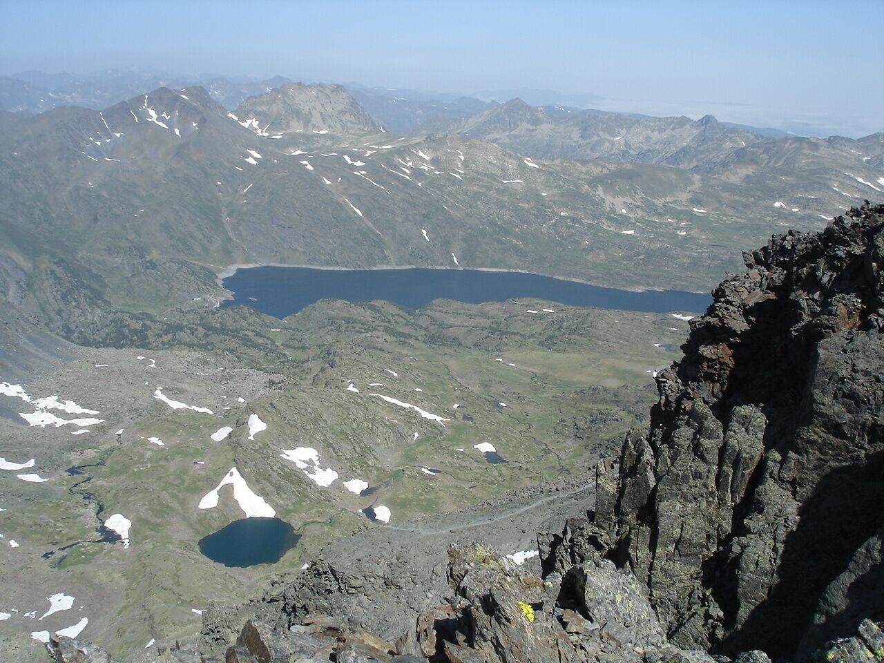 A mountainous landscape with a lake, rocky terrain, and a clear sky.
