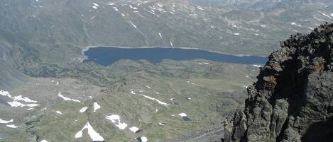 A mountainous landscape with a lake, rocky terrain, and a clear sky.