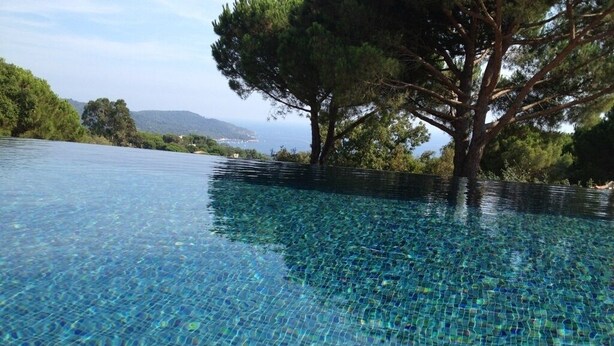 Una piscina infinita cristalina con vistas al mar y árboles.