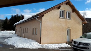 A small, single-story building with a sloped roof, a door, and multiple windows.