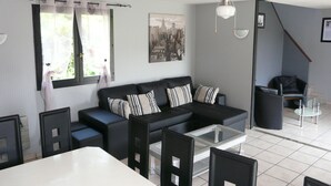 A modern living room with a black sofa, a glass coffee table, and a ceiling fan.