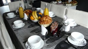 A breakfast setup with croissants, fruits, and beverages on a marble table.