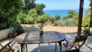 A wooden table and chairs in a garden with a view of the sea. - RENT STUDIO 30 m² fully equipped  (Coggia)