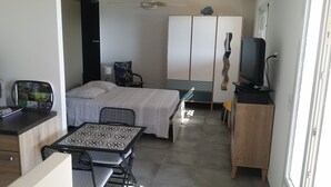 A compact hotel room with a bed, a small table, a chair, a TV, and a wardrobe. - RENT STUDIO 30 m² fully equipped  (Coggia)