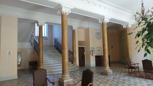 Eine prachtvolle Lobby mit Marmorboden, klassischen Säulen, einer Treppe und Sitzbereichen.