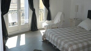 Ein Schlafzimmer mit Bett, Nachttisch, Lampe und Blick auf den Balkon.