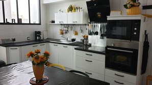 A modern kitchen with white cabinets, a black countertop, and a dining table with a vase of flowers.