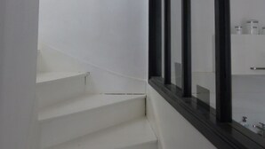 A staircase with white walls and a black-framed window.