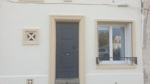 A building with a dark blue door, a window with a black wrought iron balcony, and a beige wall with a number '12' sign.