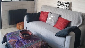 A modern living room with a sofa, a patterned throw, a round mirror, and a framed picture on the wall.