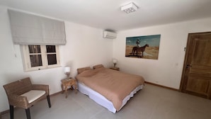 Une chambre à coucher avec un lit, une chaise, une table de chevet, une fenêtre et une porte.