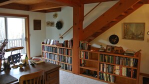 A cozy reading room with wooden bookshelves, a desk, and a staircase.