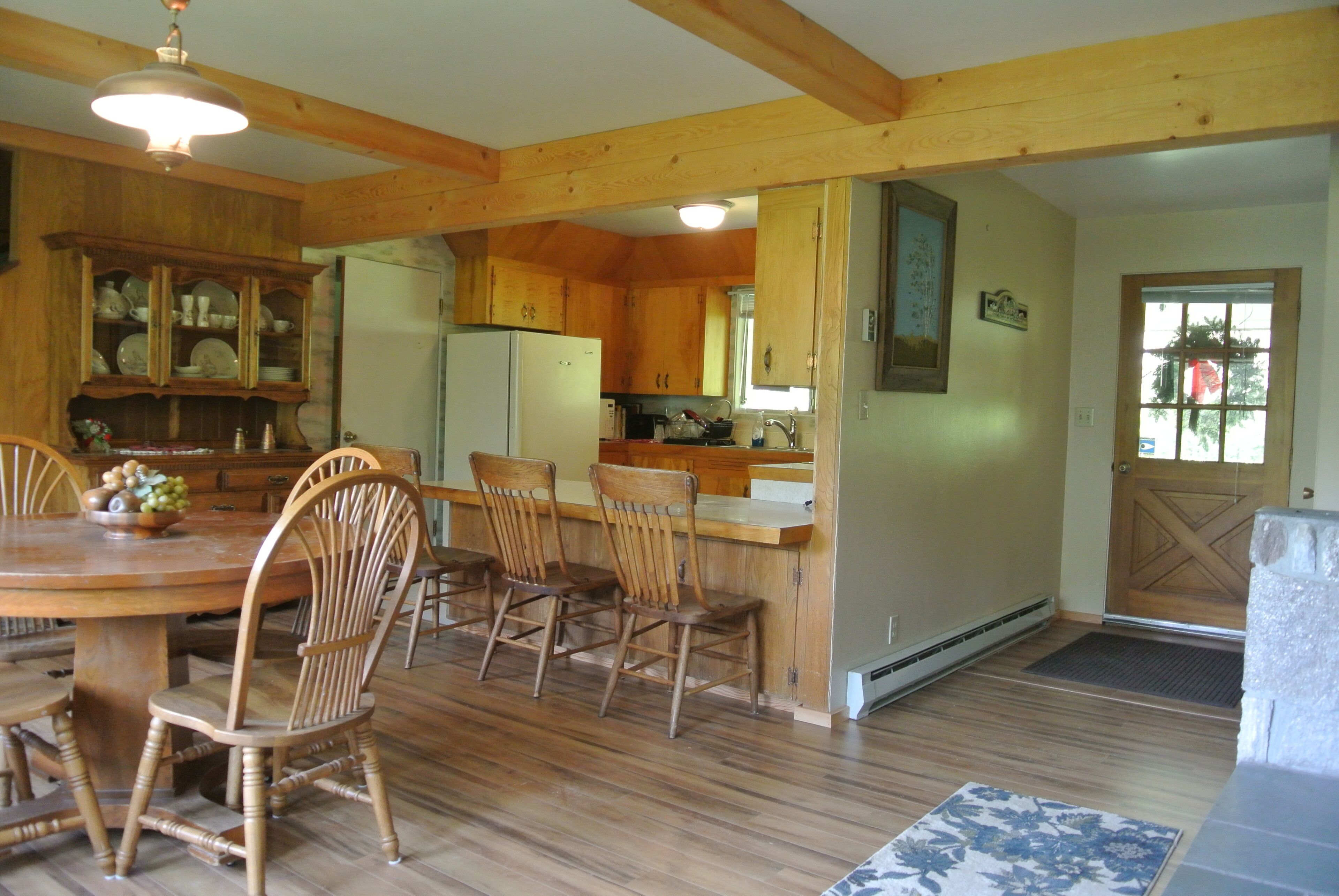 A wooden dining area with a table and chairs, a kitchen with wooden cabinets, and a door with a window view.