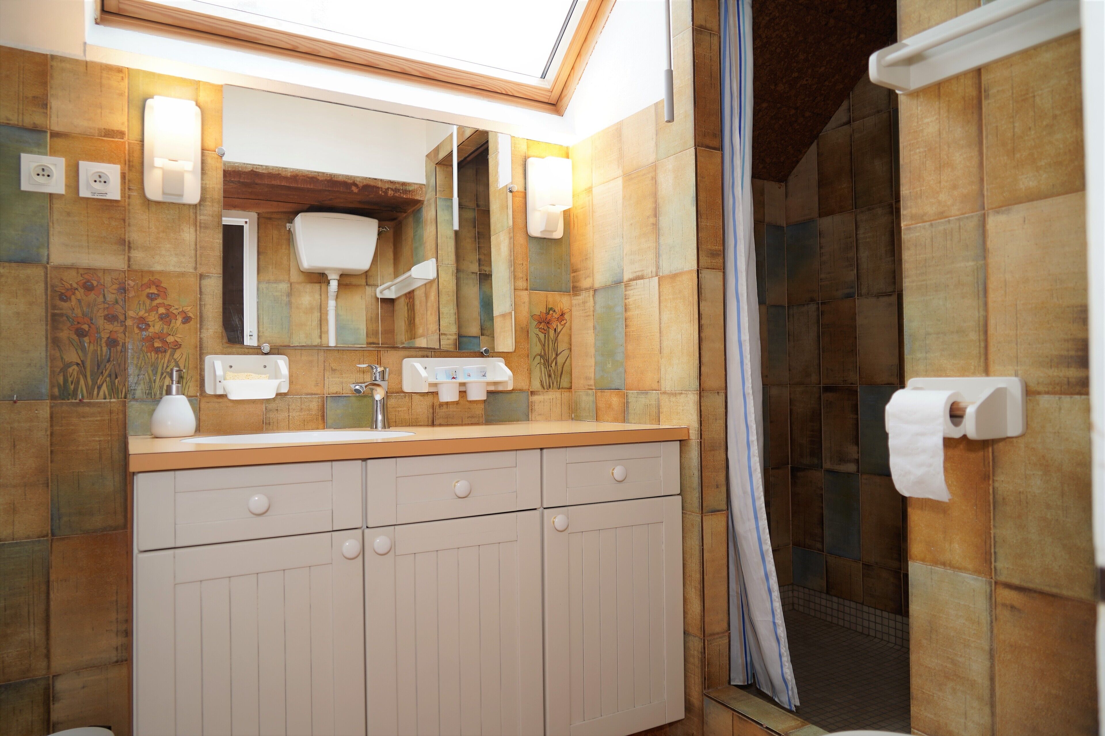 Un baño con tocador de madera, dos lavamanos, un espejo y una zona de ducha.