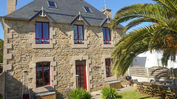 A stone building with a red door, multiple windows, and a small balcony.