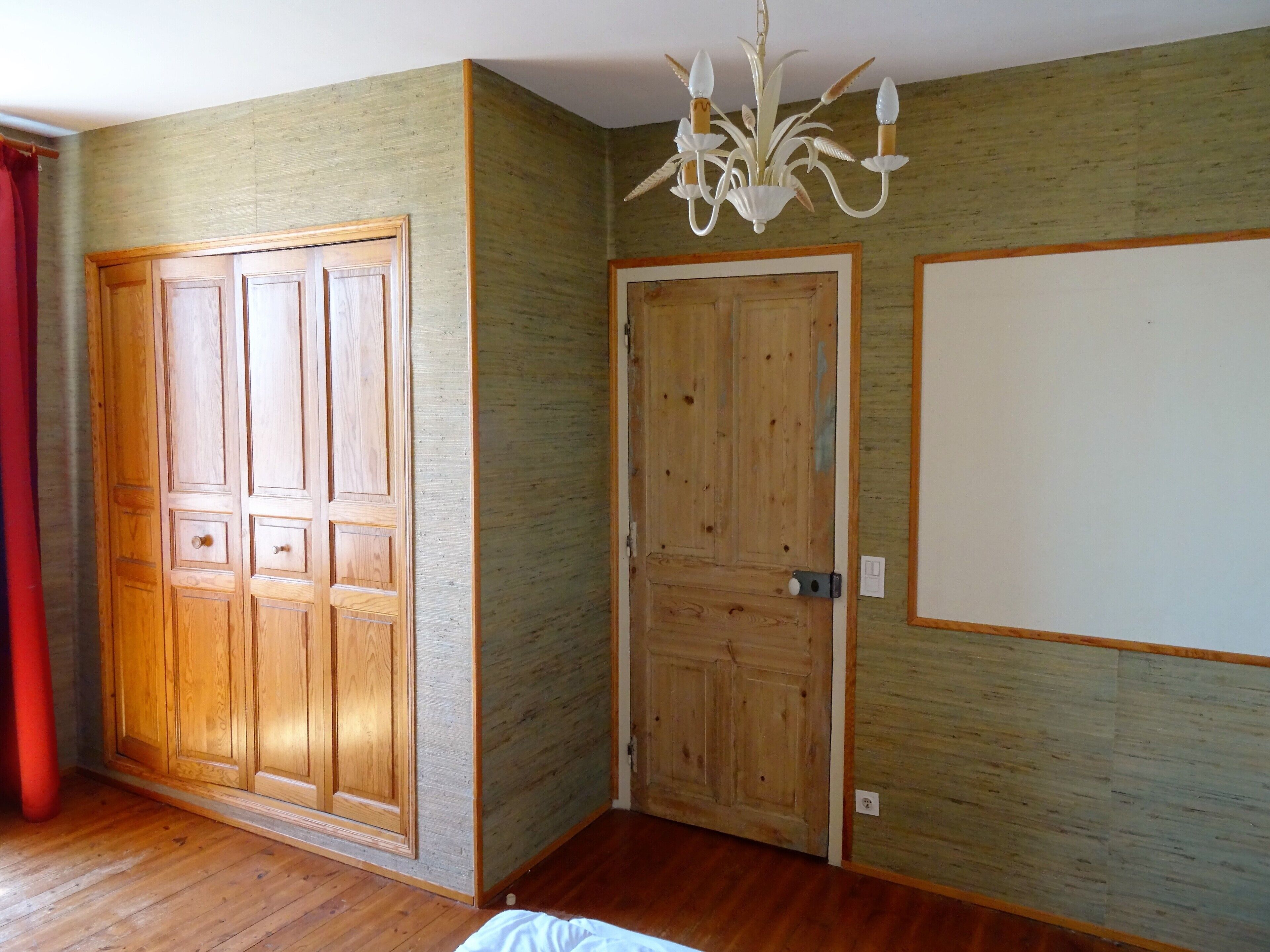 A room with wooden doors, a chandelier, and a red curtain.
