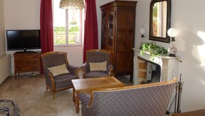 A living room with a television, two armchairs, a wooden cabinet, and a dining table.
