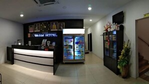 A reception area with a reception desk, a refrigerator stocked with beverages, and a wall-mounted television. - Tambun Warm Hotel (Ipoh)