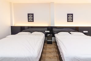 A hotel room with two single beds, a small bedside table with a phone, and a wall-mounted light. - Tambun Warm Hotel (Ipoh)