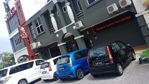 A building with a KFC sign, a sign for 'Tanbun Waram Homestay', and several parked cars. - Tambun Warm Hotel (Ipoh)