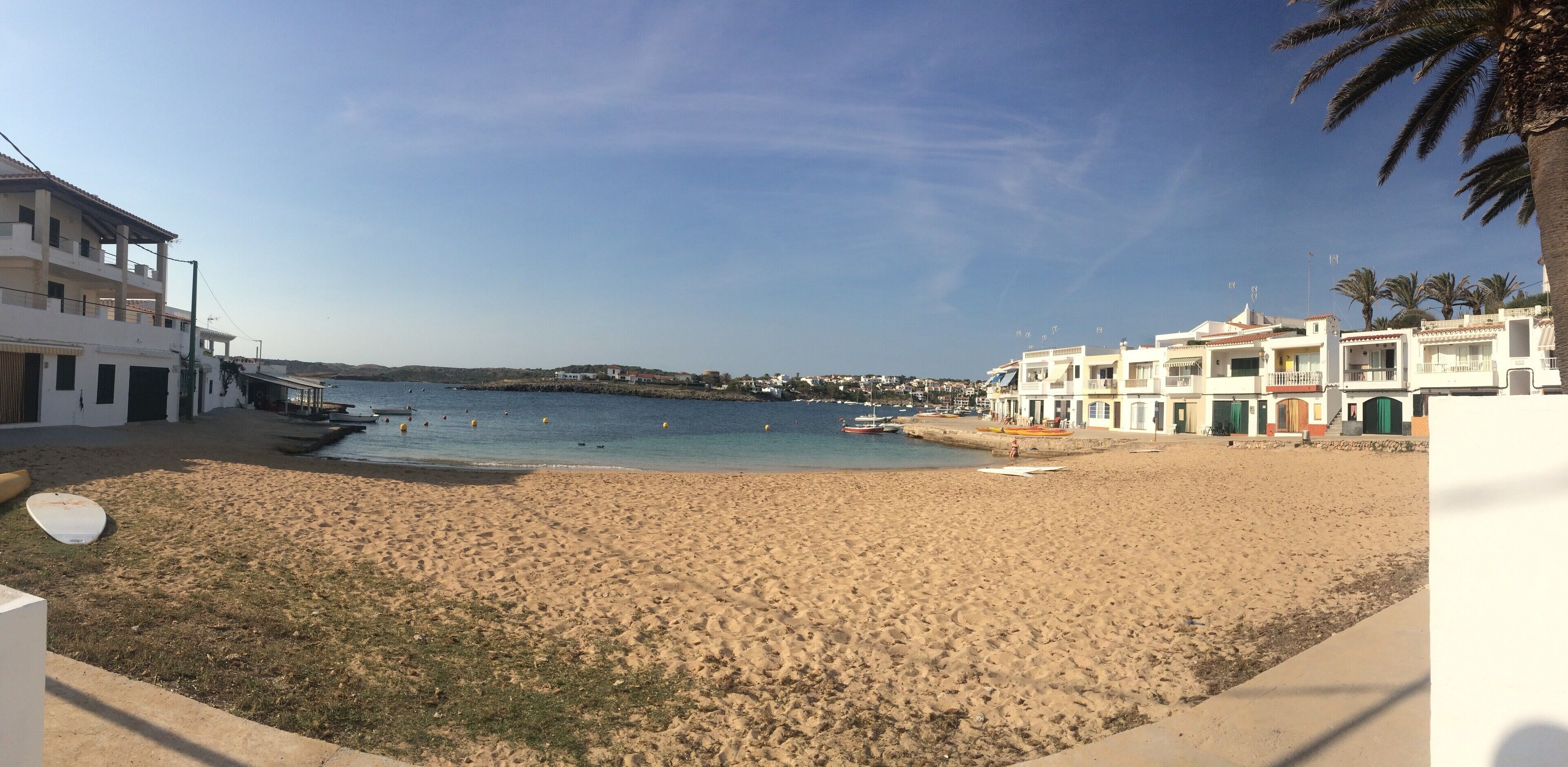 A beach with a sandy shore, a few boats, and buildings with balconies overlooking the sea.