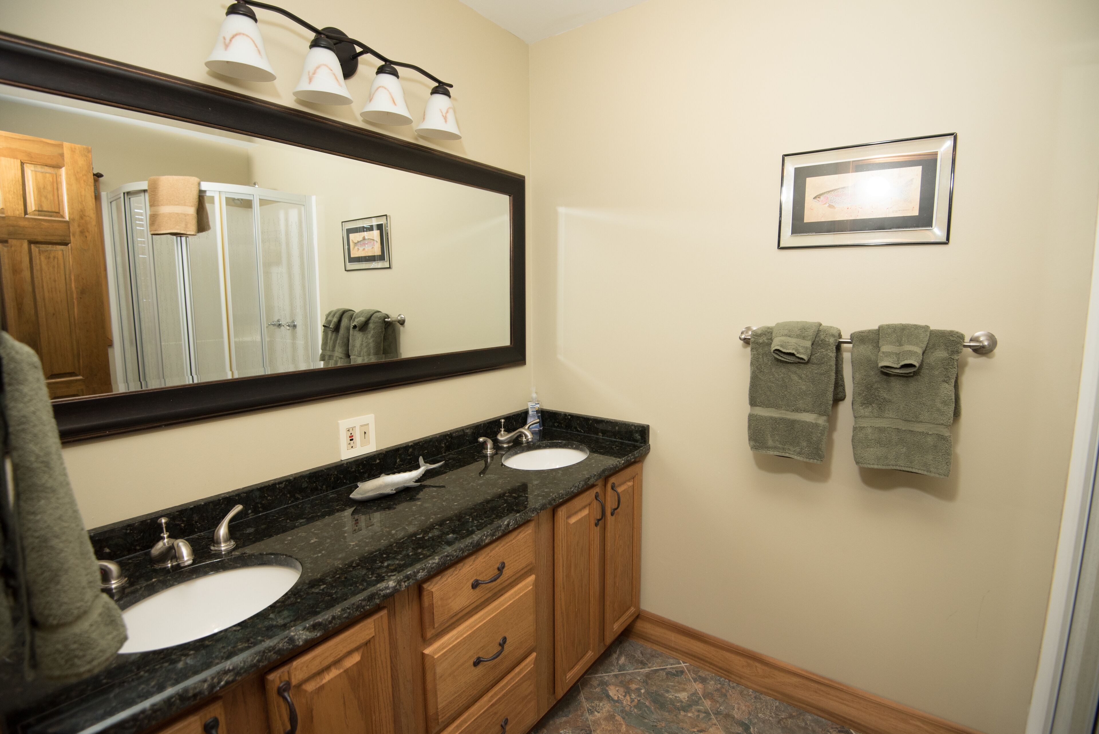 A bathroom with two sinks, a large mirror, and wooden cabinets.