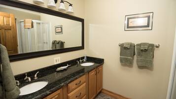 A bathroom with two sinks, a large mirror, and wooden cabinets.