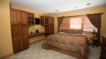 A bedroom with a large bed, wooden cabinets, a desk, and a window with curtains.