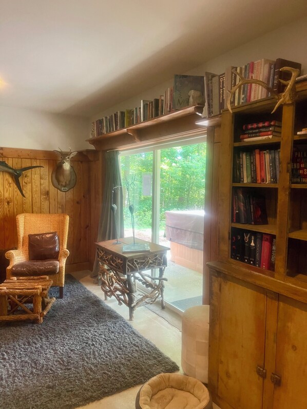 A cozy room with a wooden chair, a bookshelf, and a view through a glass door.