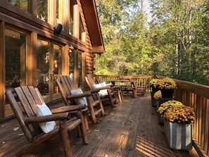 Eine Holzterrasse mit Blockstühlen und Tischen, umgeben von einem Wald.
