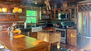 Una cocina rústica con armarios de madera, un refrigerador de acero inoxidable y un comedor con mesa y sillas de madera.