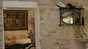 Une pièce aux murs de pierre, avec un plafond blanc, un canapé, une chaise et un miroir accroché au mur.