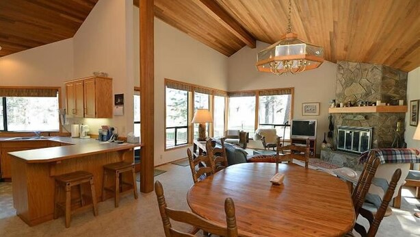 A spacious kitchen with wooden cabinets, a large island, and a dining area with a round table and chairs. - Air Conditioned/Unobstructed View of Golf Course (Black Butte Ranch)