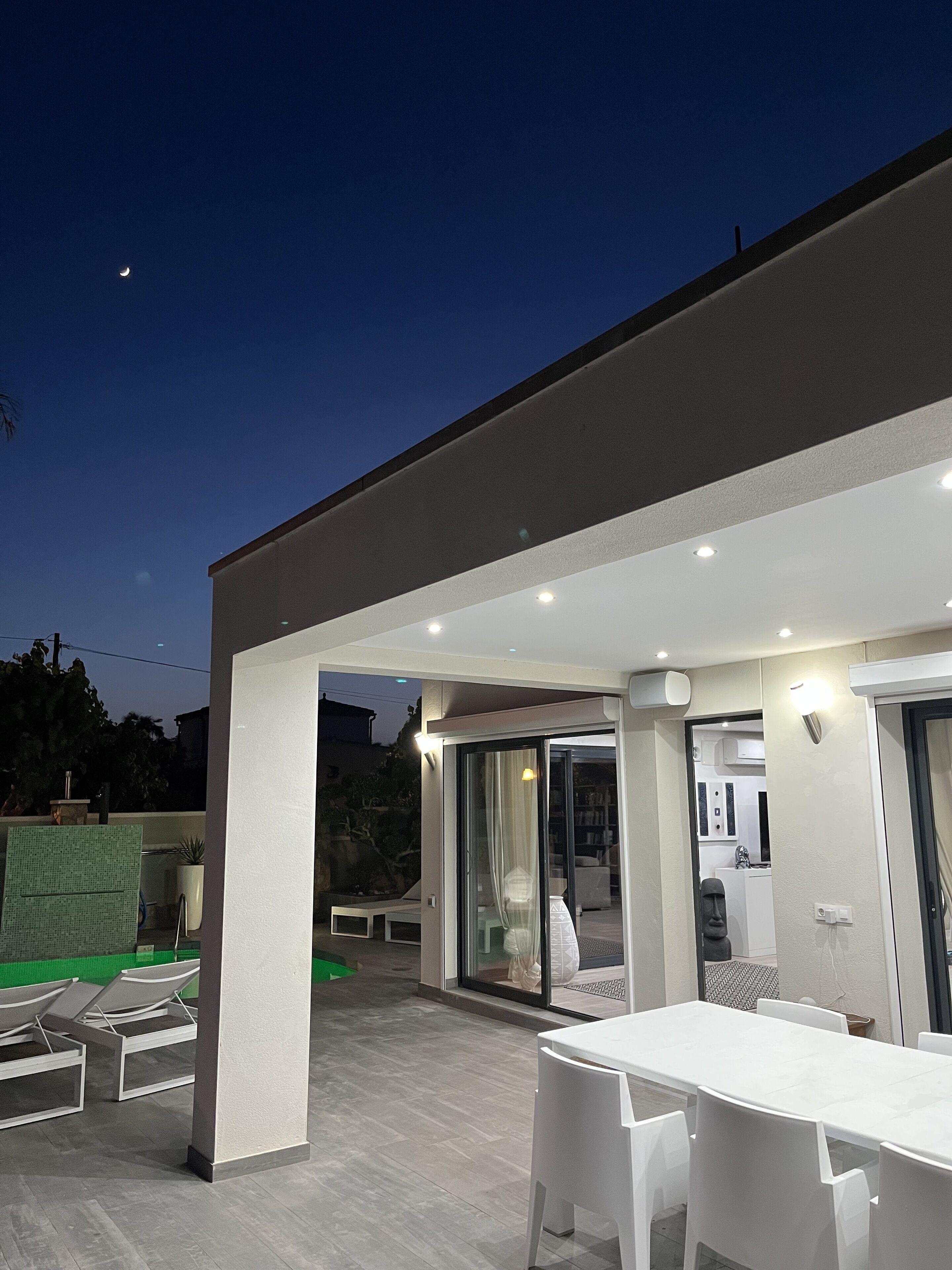 An outdoor patio area with a dining table and chairs, a covered seating area, and a view of a modern building.