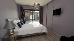 Ein modernes Hotelzimmer mit einem großen Bett, einer Nachttischlampe und einem an der Wand montierten Fernseher.
