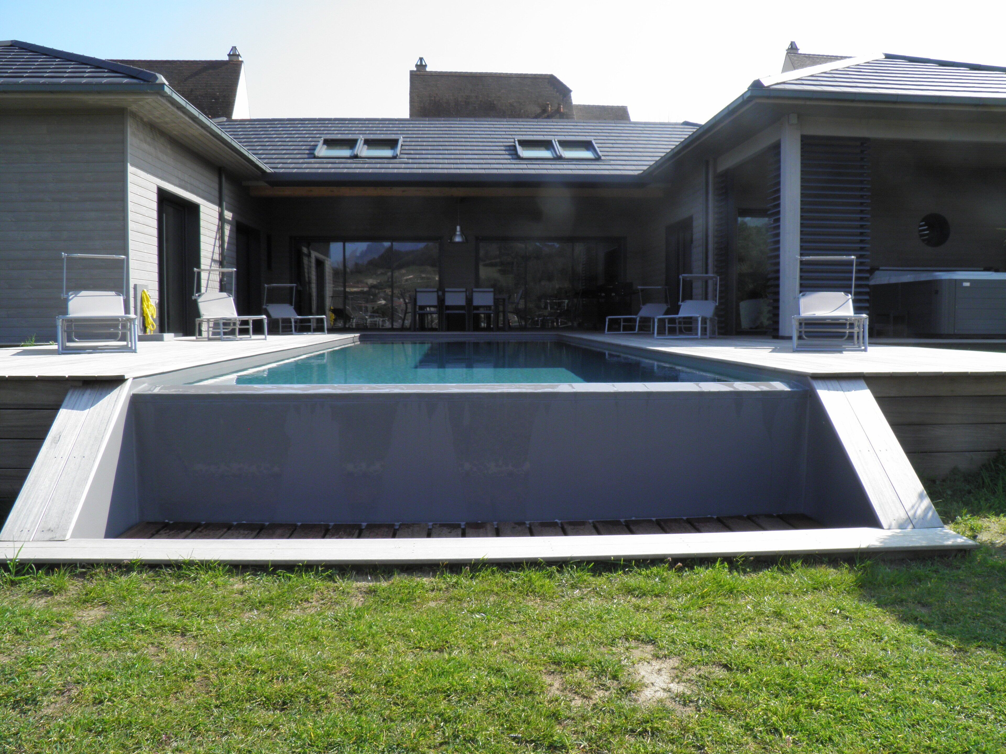 Une maison moderne dotée d’une piscine, d’un espace salon extérieur et d’un patio couvert.