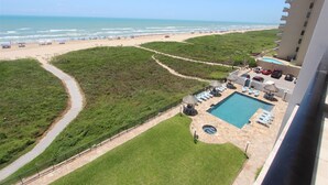 Ett semesterhotell med pool, solstolar och utsikt över stranden.