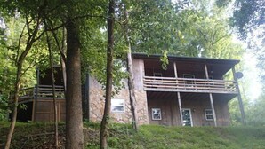 Een blokhut met twee verdiepingen, een gevel van steen, een balkon en een houten terras.