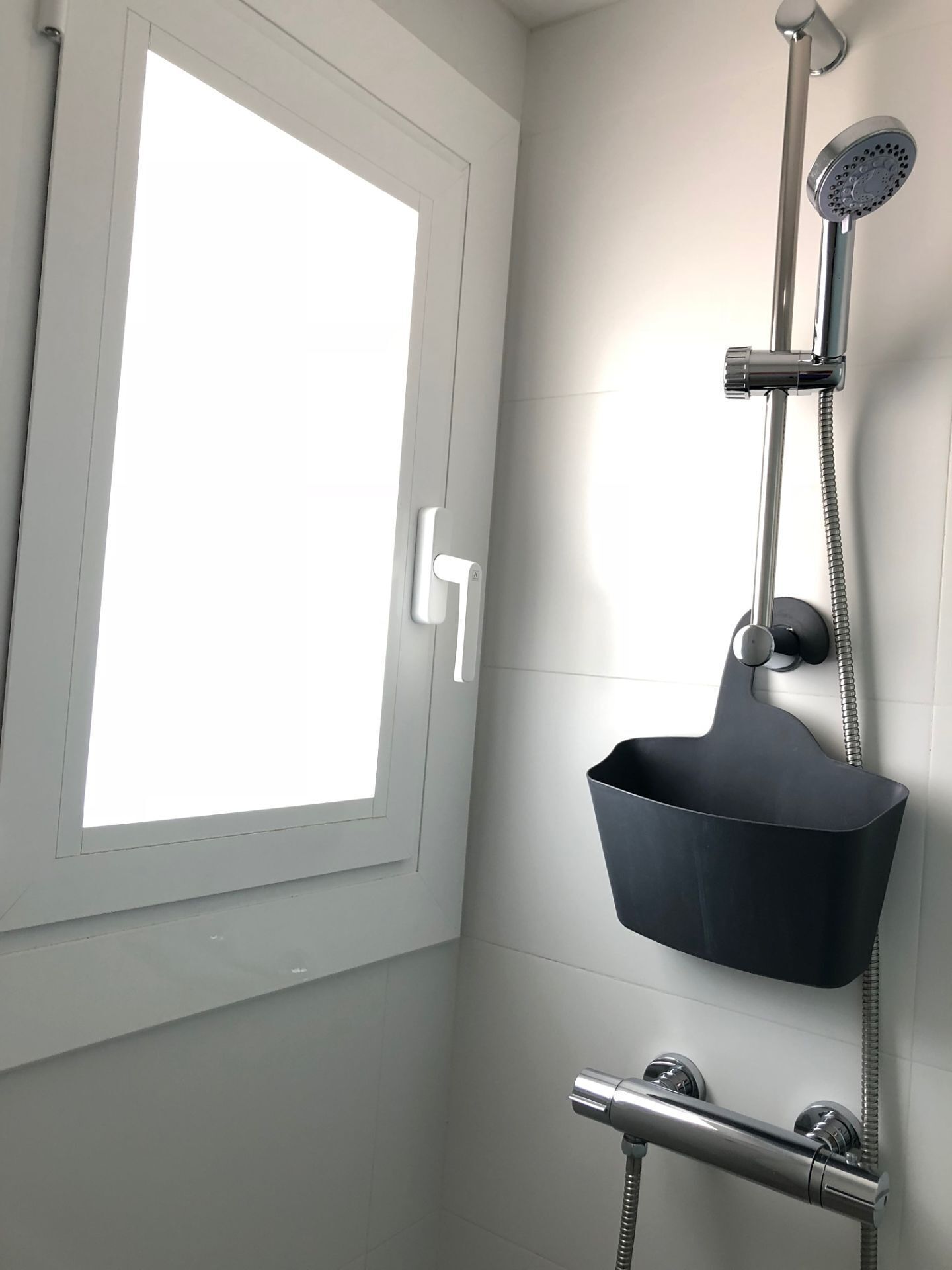 Un baño con ducha, ventana y toallero.