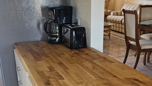 A kitchen with a wooden countertop, a coffee maker, and a toaster. There is a dining area with chairs and a table in the background. - Waterfront home on deep water canal (Hernando Beach)