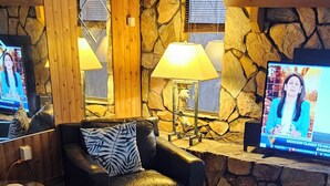A cozy living area with a stone wall, leather furniture, and a television displaying a news program. - Waterfront home on deep water canal (Hernando Beach)