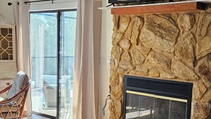 A bedroom with a large bed, a stone fireplace, a TV on a shelf, and a view of the outdoors through a sliding glass door. - Waterfront home on deep water canal (Hernando Beach)